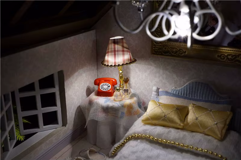 miniatuurne magamistuba, kus on voodi, öökapp, lamp ja punane telefon
