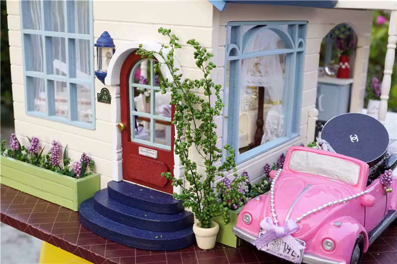 miniatuurne nukumaja koos roosa autoga ja lilledega