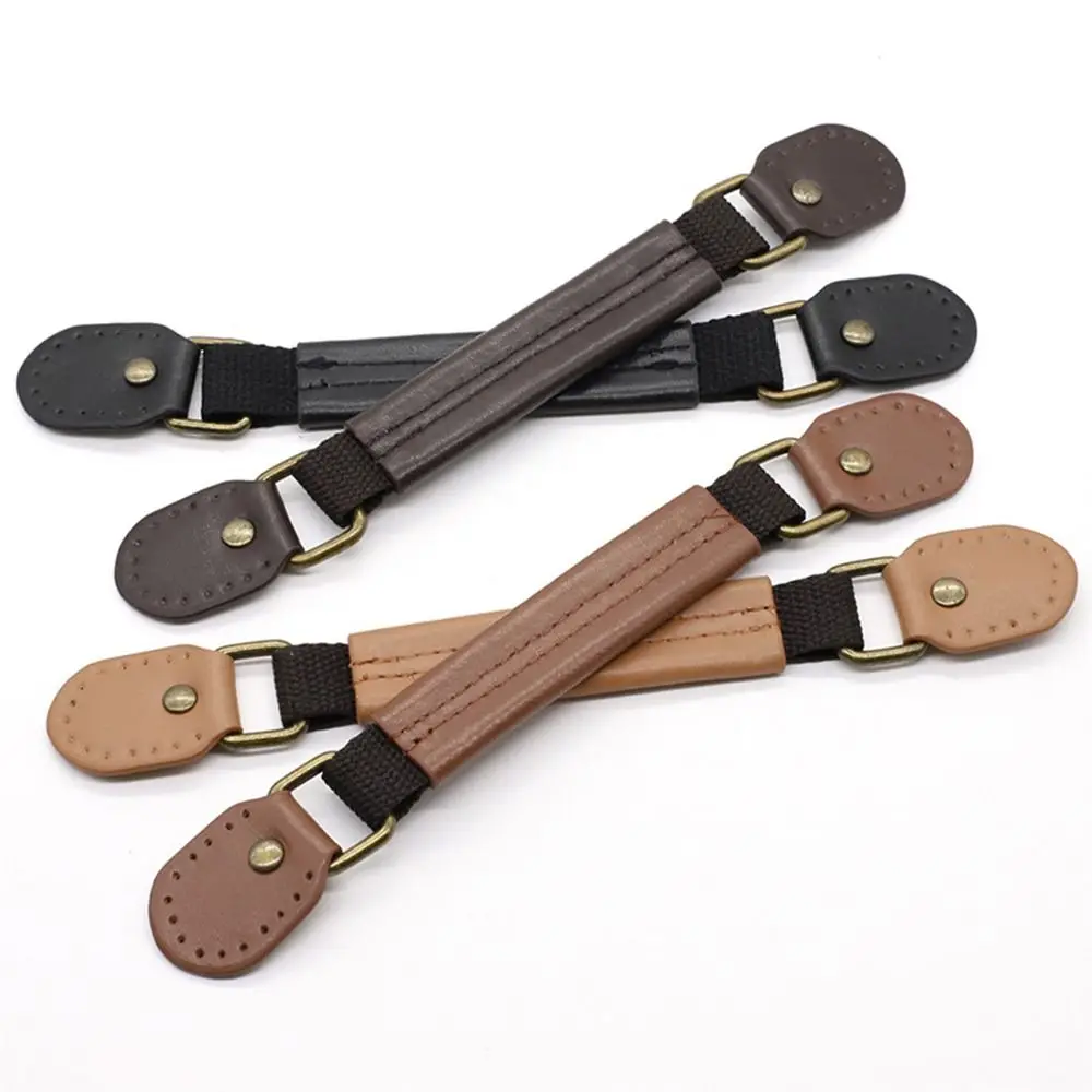 Kolm erinevat värvi kohvri või koti asendussanga, mustast kunstnahast ja metallist detailidega, asetatud valgele taustale.