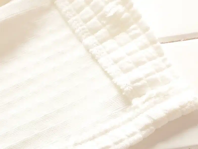 valge tekstuuriga riide detail, millel on triibulised ja ruudulised mustrid