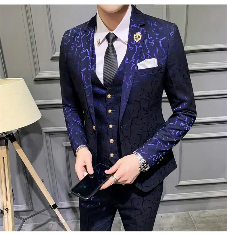 Tumepunane mustriline ülikond elegantsete kuldnööpidega, sobib ideaalselt hallil taustal.