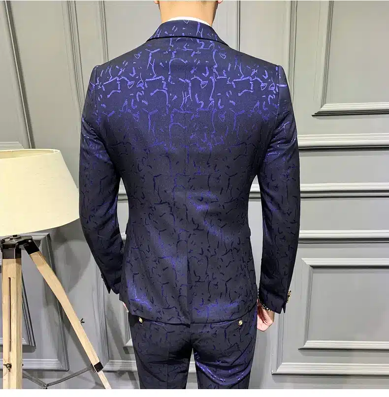 Tumepunane mustriline ülikond, mille seljal on elegantne mustriga kangas ja luksuslik läige, hallil taustal kaunistamas mehe figuuri. Stiilne välimus rõhutab detailide jõudu.