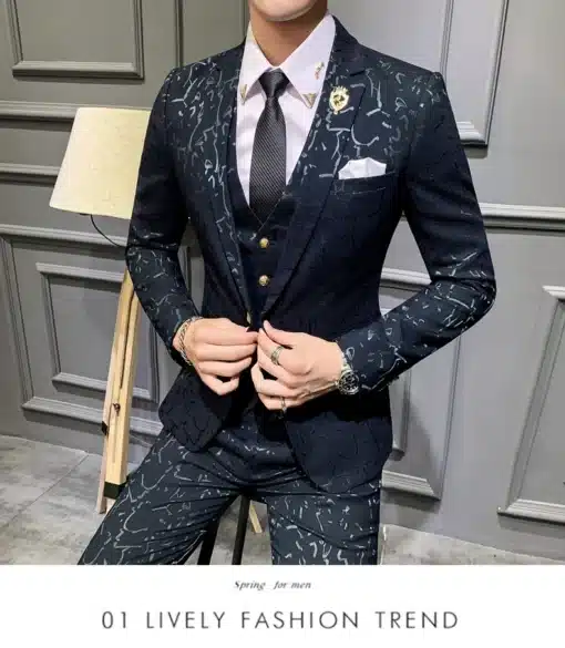 Mees kannab tumepunast mustrilist ülikonda, millel on detailne valge muster. Taust on elegantne sisemus heleda seinaga ja modernse põrandalambiga.