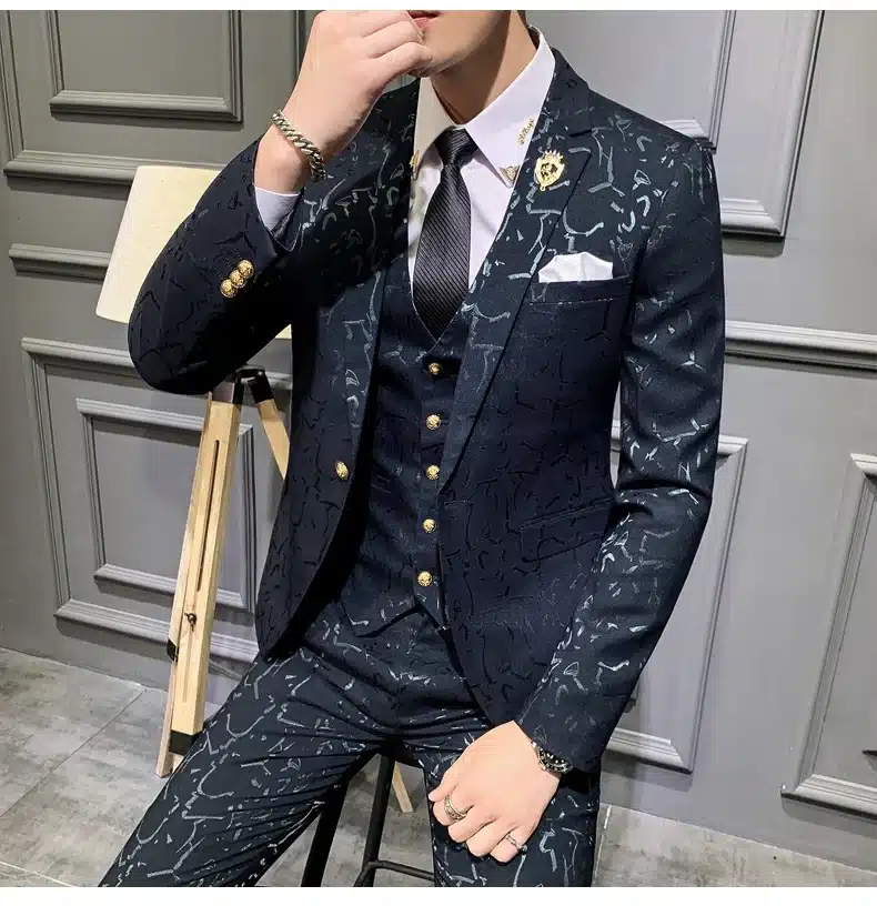 Mees kannab stiilset tumepunast mustrilist ülikonda neutraalse tooniga tausta ees, rõhutades ülikonna elegantset ülesehitust ja luksuslikku väljanägemist.