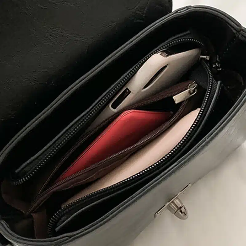 Väikesed crossbody kotid sangaga, avatud pealtvaates, sisaldades mitut taskut, nullužru ja telefoni, hallilt pinnalt peegeldusega ja elegantsest mustast materjalist.