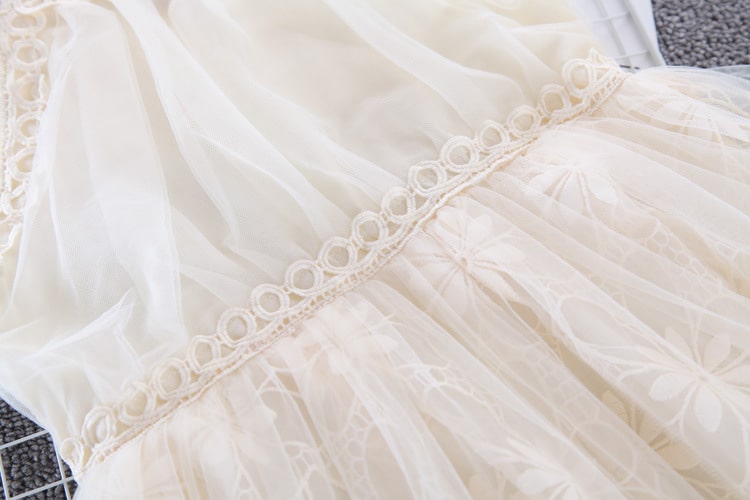 Kreemikasvalge pidulik tüdrukute kleit, mis on valmistatud pehmest tüllmaterjalist ja kaunistatud õrna pitsiga. Kleidi detailideks on lillemustriga tikand ja elegantne vöökoht, mis lisab šikki välimust.