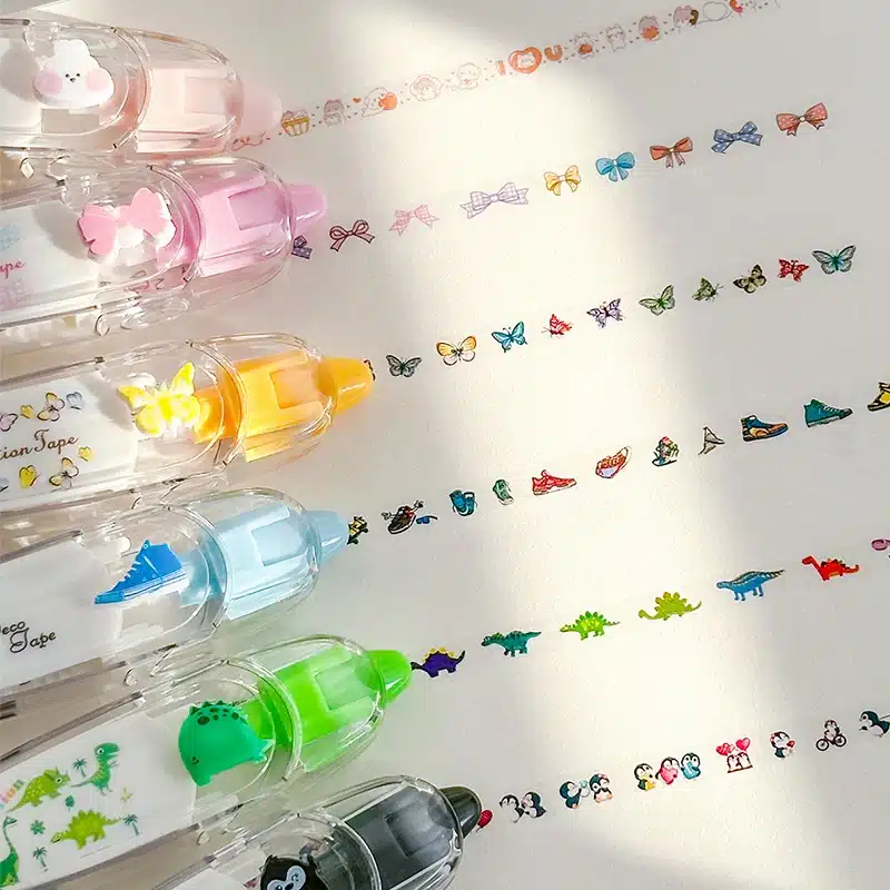 Lõbusate piltidega tempelpliiatsid erinevates värvides, asetatud valgele paberile koos mitmesuguste värviliste templimustritega, sealhulgas liblikad, masinad ja loomad.