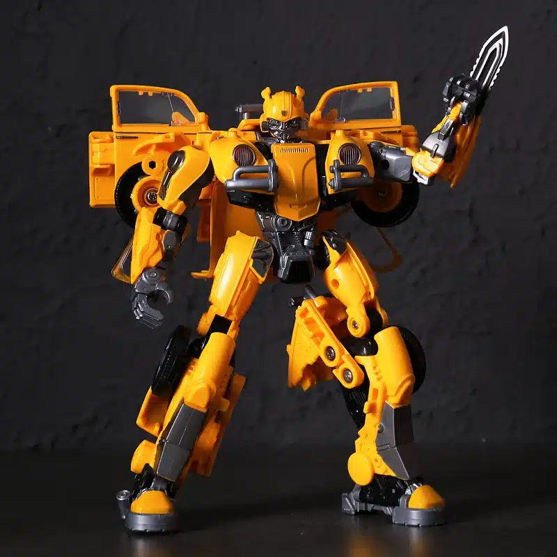 Mustal taustal on erekollane Transformeeruv Transformer Bumblebee mänguasi, millel on ulatuslikud detailid ja sihver plaat, hoides kätt ähvardava tera poosis. Mänguasi kombineerib mustaid ja halli toonid harmooniliselt, esitledes nii roboti- kui autovormi elemente.