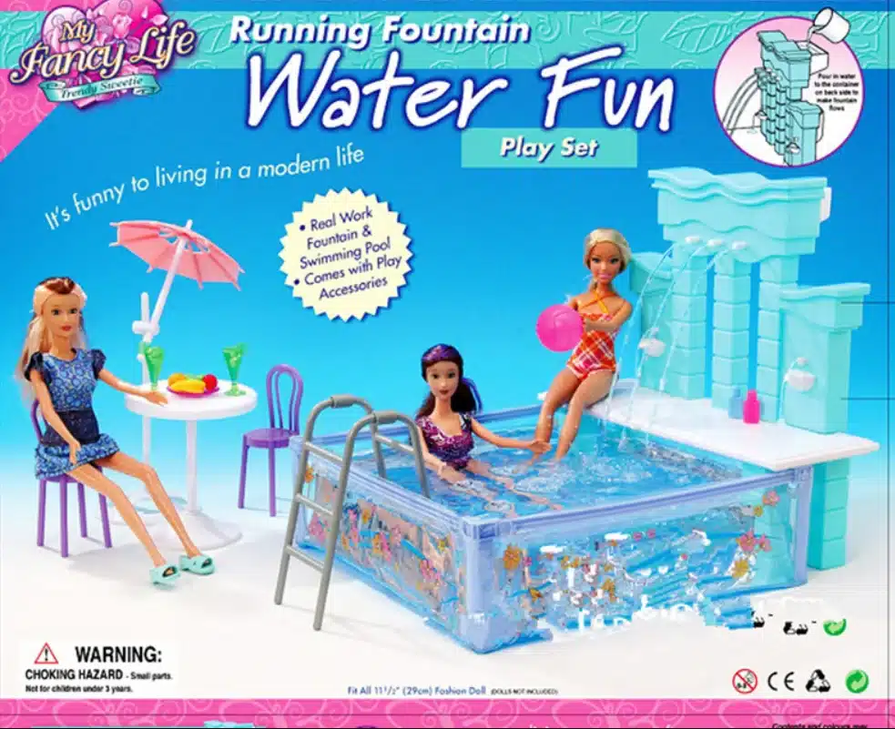Kolm Barbie-nukku on mänguasja ujumisbasseini komplektiga. Nukud istuvad basseinis ja selle kõrval, ümbritsetuna suvemeeleolus aksessuaaridega. Taust on sinine ja mängulise disainiga, lisatud on purskkaevu element, mis rõhutab komplekti funktsionaalsust.