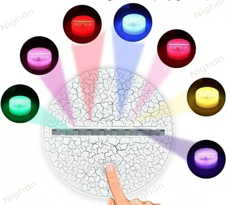 Värvilised valguskiired, mis kiirgavad 3D lamp 'Koer' erinevates toonides, alusest ülespoole. Lamp asub valge pragunenud mustriga taustal, keskmes on puudutamiseks mõeldud sensor.