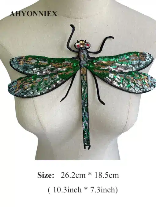 Suur pealetriigitav kiil, millel on rohelised, kuldsed ja sinised litrid, eksponeeritud mannekeeni rinnal, neutraalsel taustal.