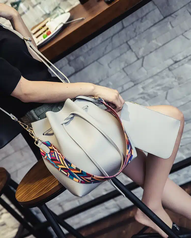 kunstnahast crossbody kott värvilise mustrilise sangaga, mille kõrval on väike rahakott