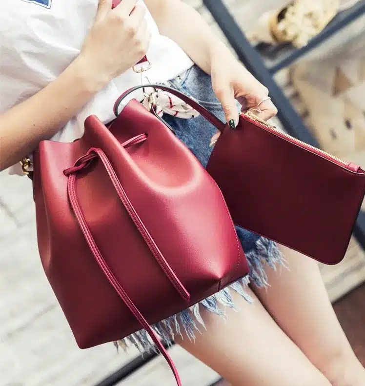 punane kunstnahast crossbody kott ja väike kott, mida hoiab naine teksapükstes