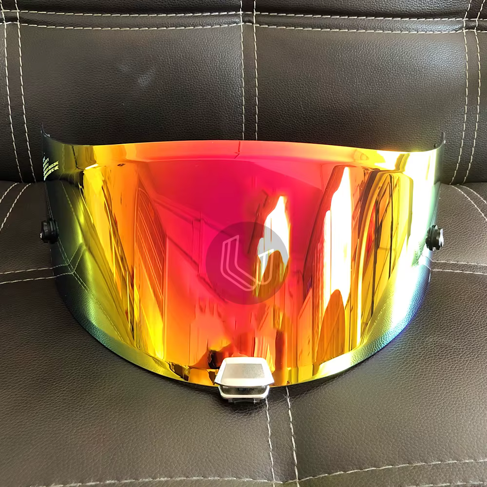 Iridescent HJC RPHA-11/70 helmet visor displayed on brown leather surface, reflecting vibrant orange and red hues.