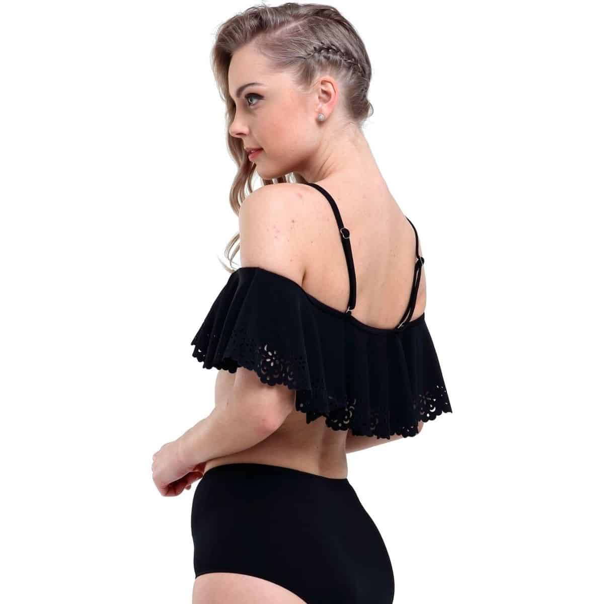 Naine kannab musti volangiliste varrukatega bikiine valgel taustal. Elegantne top varrukatega ja sobivad bikiinipüksid loovad stiilse ja kaasaegse ilme.