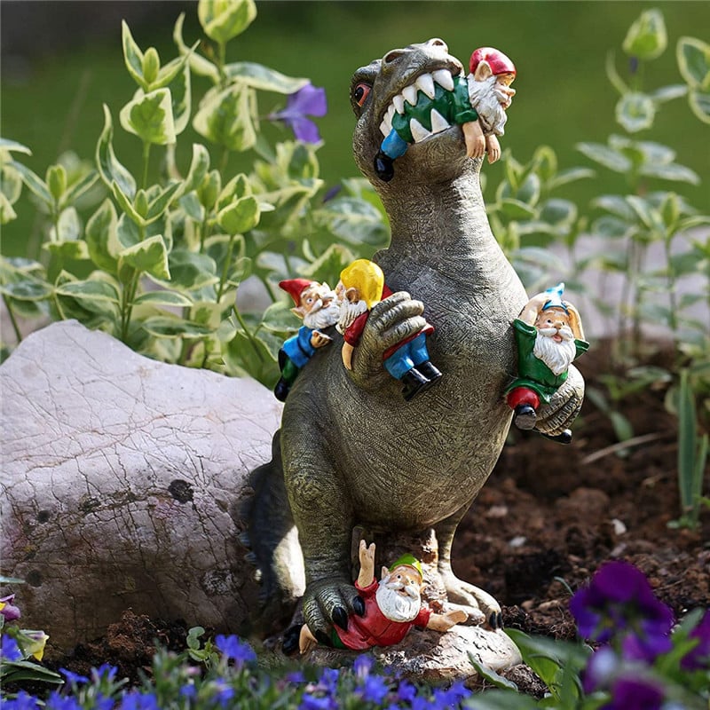 Kuju dinosauruse ja pöialpoistega kujutab suure dinosauruse mängulist stseeni, kus erivärvilised pöialpoisid rühmituvad dinosauruse ümber, roheliste taimede ja lillede taustal, luues lõbusa ja fantaasiarikka aiadekoratsiooni.