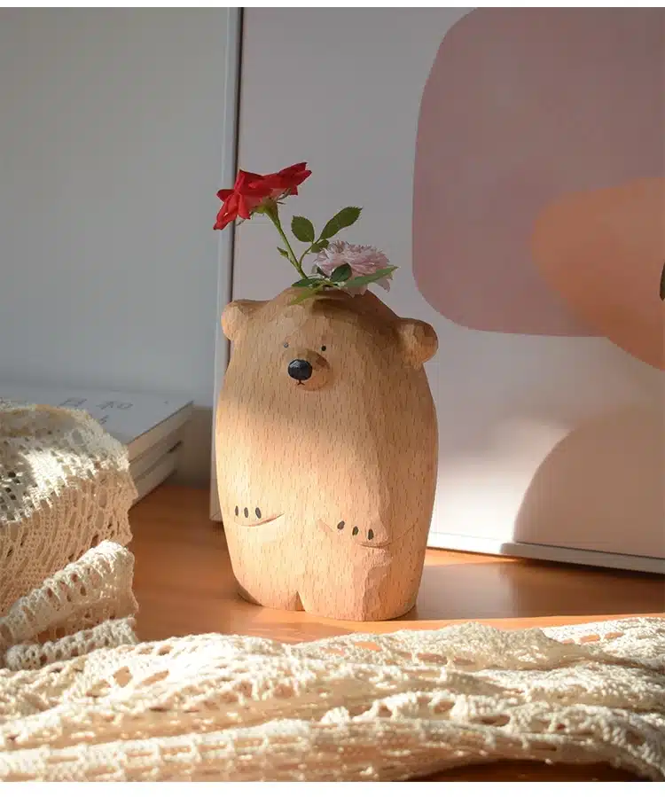 puidust karu kujuline vaas, mille sees on punane ja roosa lill