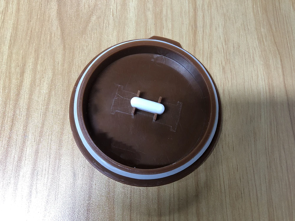 pruun plastmassist kruusi kaas valge nupuga puidust pinnal