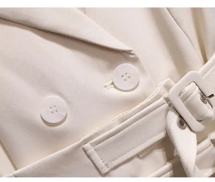 Beeži pintsakkleidi detailne ülevaade, mis näitab elegantseid nuppe ja vööd. Riide kangas on sile ning õrn toon sobib hästi pidulikeks sündmusteks.