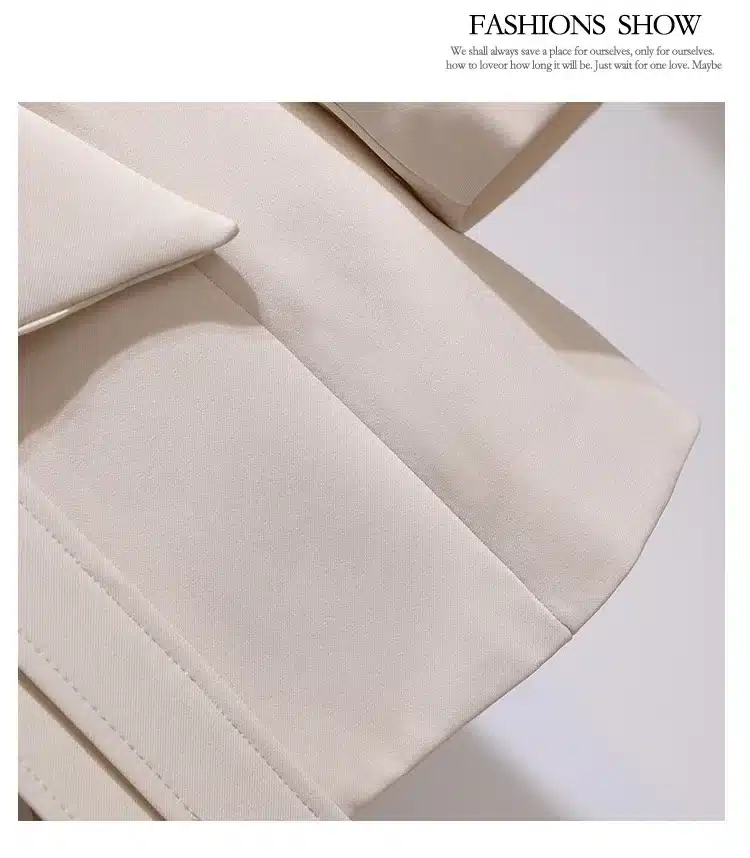 Beež pintsakkleit, millel on detailne vaade kangale ja õmblustele, tuues esile kleidi elegantsuse ja stiilsuse.