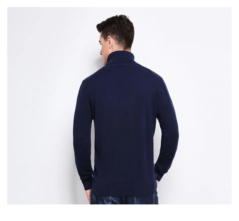 mees seljaga kaamera poole, seljas tumesinine kõrge kaelusega pullover