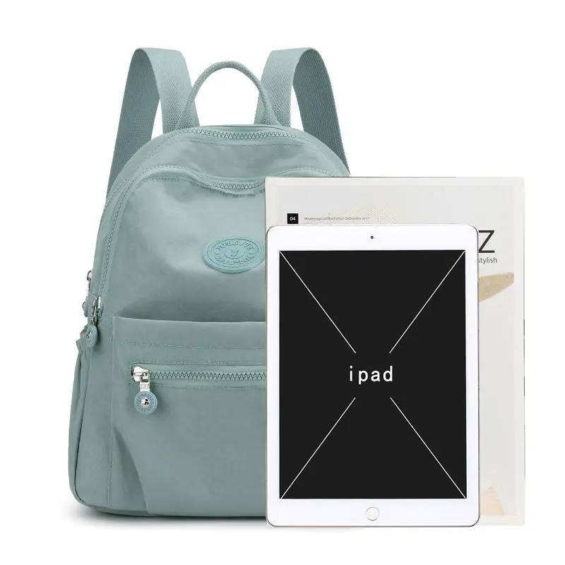 väike ühevärviline seljakott mitme taskuga, kõrval iPad ja ajakiri