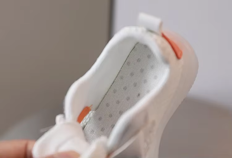 valge laste tossu sisemus, millel on pehme vooder ja oranž detail