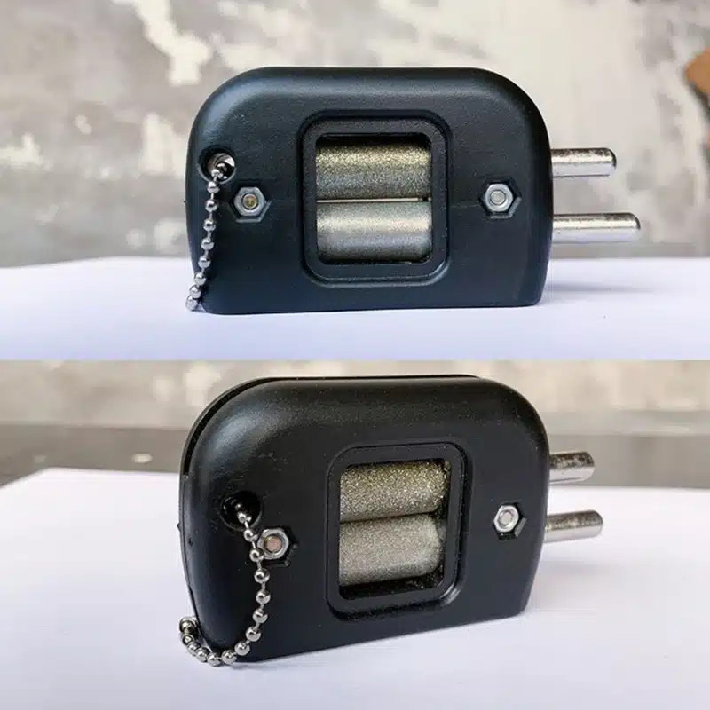 Uisuteritaja must plastikust korpus kahe metallist teritusrulliga, millel on keti kinnitus detailina. Toode asetatud valgel pinnal halli betoonseina taustal.