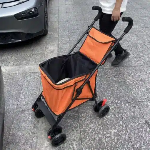 oranž kokkupandav ostukäru musta raamiga, seisab tänaval auto kõrval
