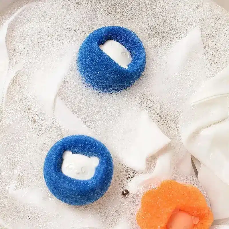 sinine ja oranž karvaeemaldaja pesumasinas koos valge pesuga
