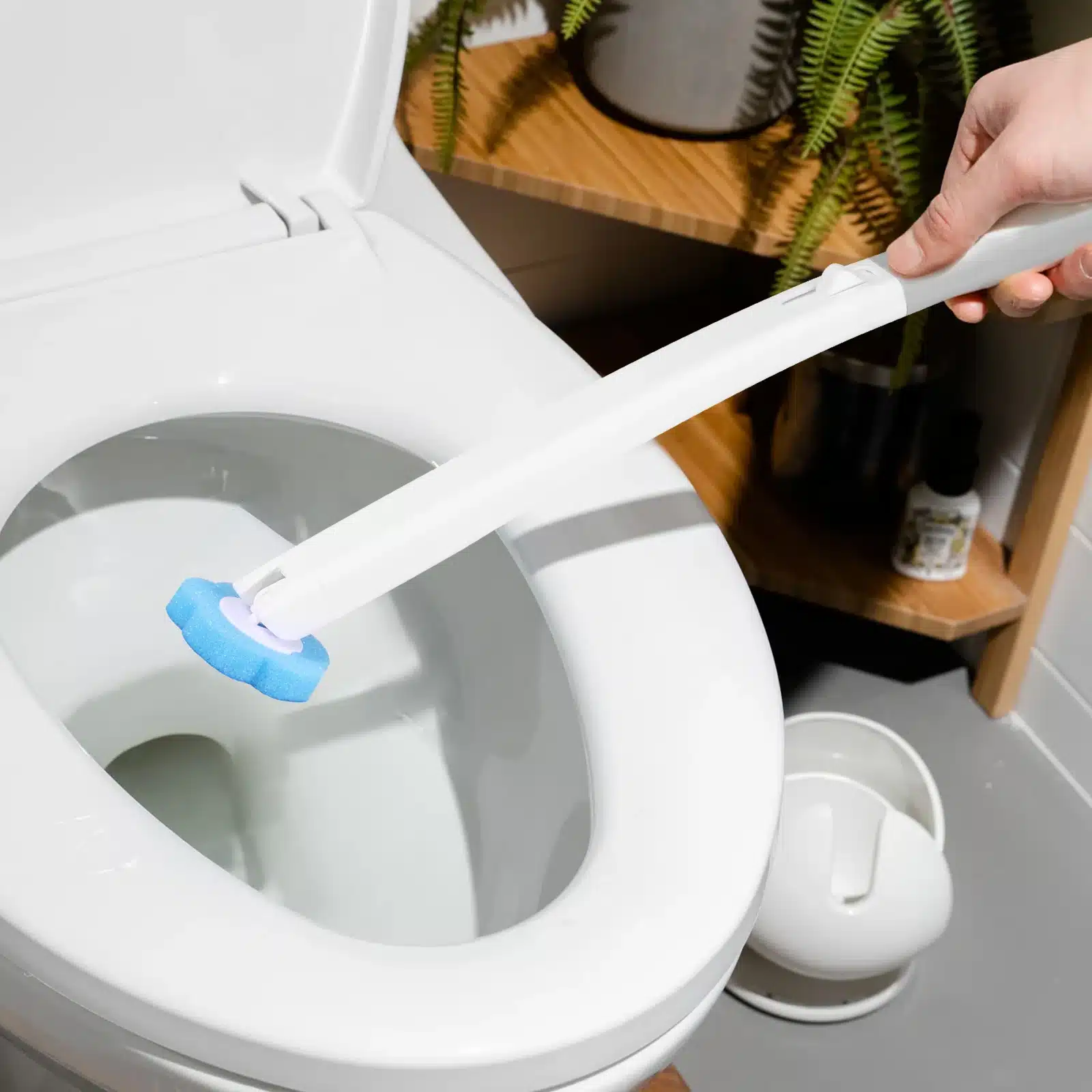 käsi hoiab vahetatava otsikuga wc puhastusharja, millel on sinine puhastusotsik