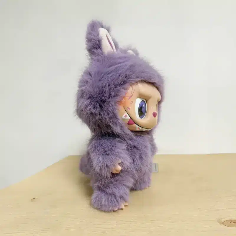 lilla karvase kostüümiga monster nukk puidust pinnal