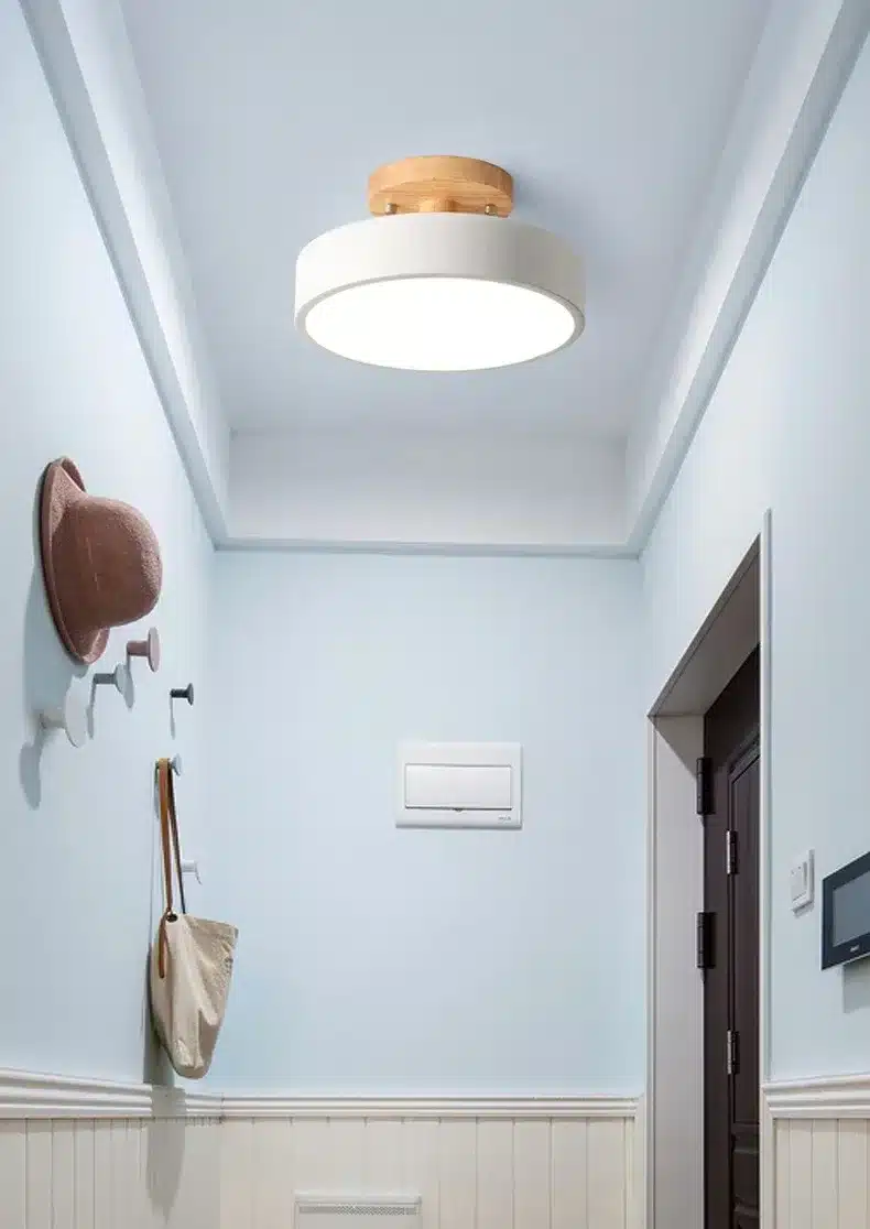 valge ümmargune laelamp puidust detailidega heledas koridoris