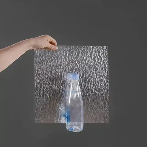 käsi hoiab läbipaistvat tekstuuriga plaati, mille taga on plastpudel