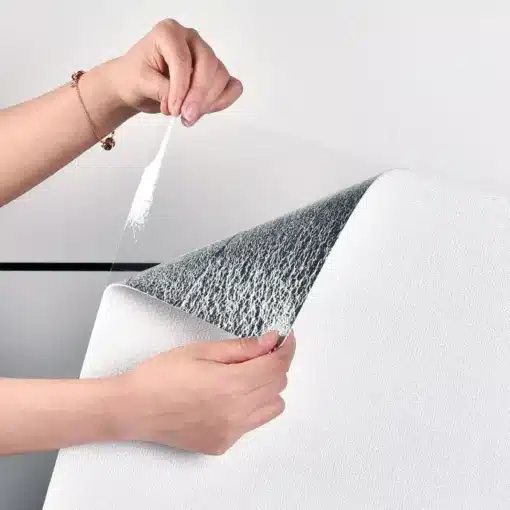 Käsi tõmbab Linane 3D tekstuuriga iseliimuvat paksu tapeeti, paljastades tapeedi all oleva kihi. Valge tapeet on sileda linase tekstuuriga ja selle tagakülg on läikiv.