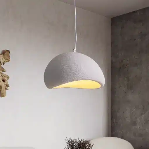 Skandinaavia stiilis LED laelamp helendab õrnas soojas valguses betoonseinalise ruumi taustal. Lamp on valge tekstuurse pinnaga ning ripub elegantselt minimalistliku disainiga interjööris.