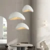 Kolm valget Skandinaavia stiilis LED laelampi ripuvad elegantses, minimalistlikus elutoas hallide seinte ja lihtsa mööbliga. Lambid loovad sooja valguse ning lisavad ruumile moderne stiili ja õhulisuse.