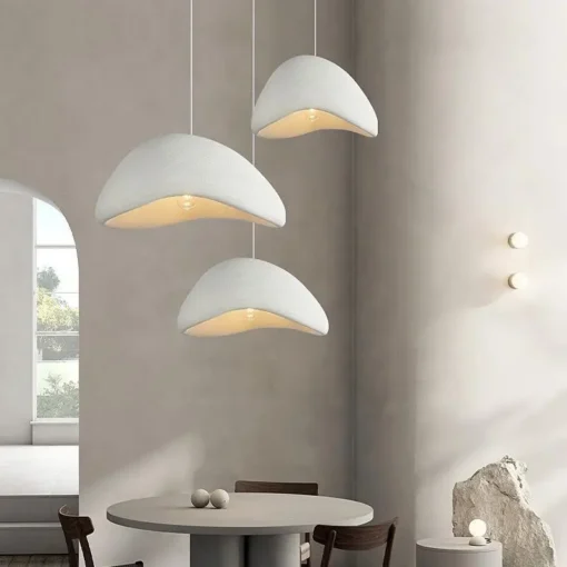 Kolm valget Skandinaavia stiilis LED laelampi ripuvad elegantses, minimalistlikus elutoas hallide seinte ja lihtsa mööbliga. Lambid loovad sooja valguse ning lisavad ruumile moderne stiili ja õhulisuse.