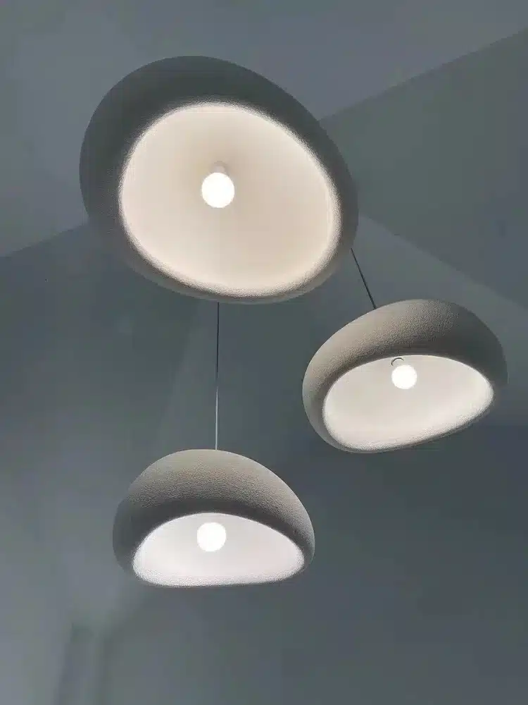 Kolm elegantset valget Skandinaavia stiilis LED laelampi, mis ripuvad siledal hallil taustal, pakkudes pehmet ja hubast valgustust.