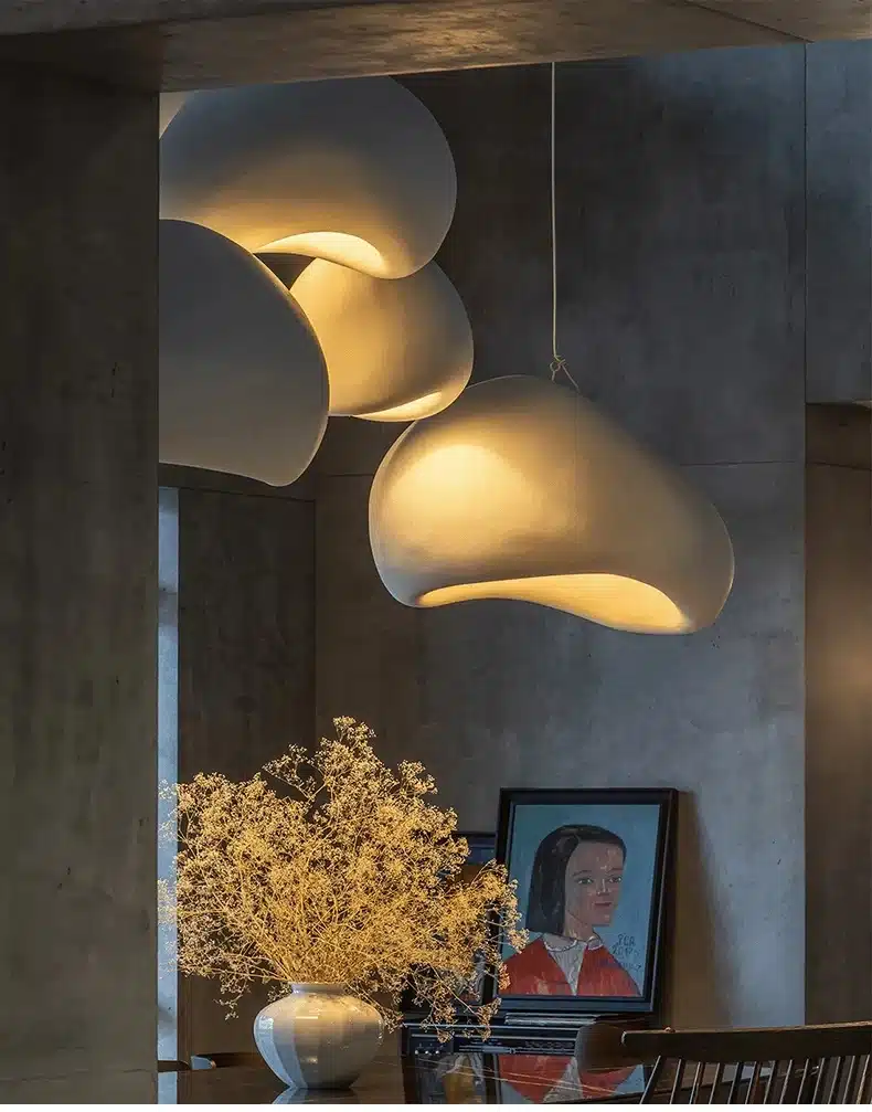 Skandinaavia stiilis LED laelamp valgustab modernset ja dekoratiivset ruumi sooja pehme valgusega, seinal maal ja laual vaas kunstlilledega.