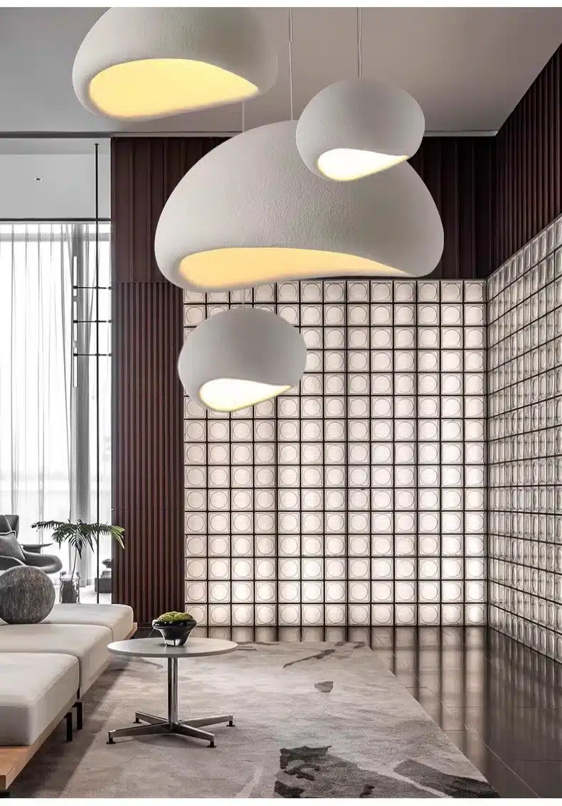 Stiilne Skandinaavia stiilis LED laelamp heleda varjundiga, mis ripub modernses elutoas puidust ja klaasplokkidest seina taustal. Laelamp loob pehme ja ühtlase valguse, rõhutades ruumi elegantset sisekujundust.