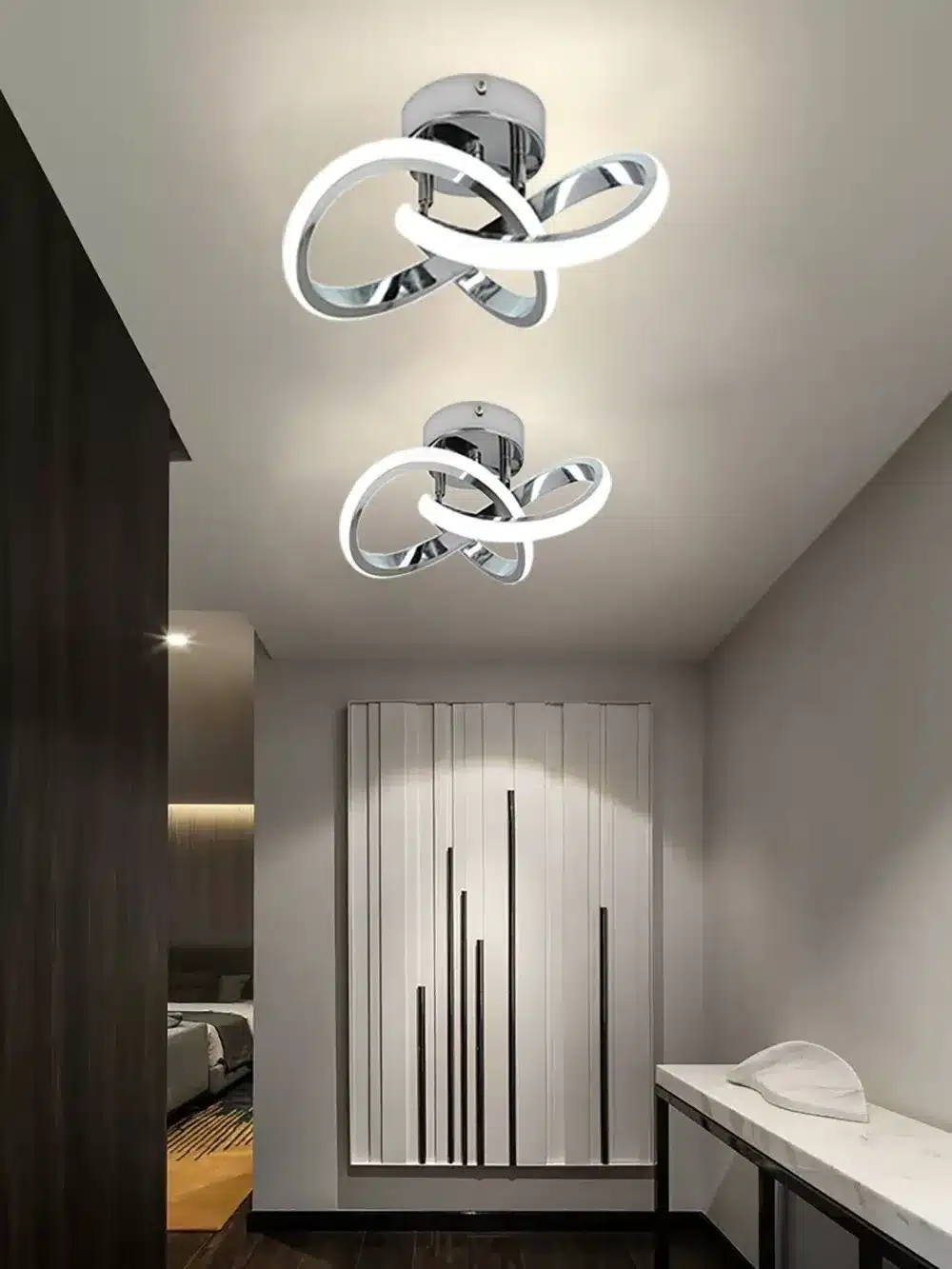 Kaks moodsat ja soodsat minimalistlikku LED laevalgustit kaasaegses siseruumis, heleda seina ja laega. Valgustid on keerukas geomeetrilises kujundis, valmistatud metalsetest materjalidest ning ümbritsetud pehme valge valgusega, mis lisab ruumile soojust ja stiili.