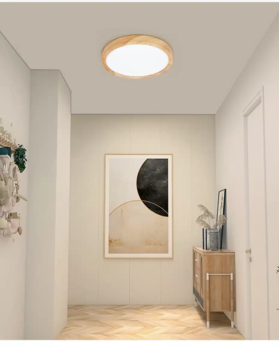 Koridoris ripub säästlik puidumustriga laevalgusti, mis kiirgab sooja valgust. Valgus paistab puitpõrandale ja heledatele seintele, rõhutades minimalistlikku sisekujundust. Puidust detailidega lamp täiendab sobivalt ruumi meeleolu.
