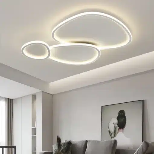 Kolmeosaline moodsad LED laelambid valge ja hõbedase viimistlusega, paigaldatud elutoa heledale lakke minimalistliku sisekujunduse taustal.