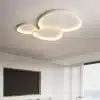 Kolm ümmargust moodsat LED laelampi elutoas, valged toonid, ühtlane valgus, minimalistlik disain valgel lael.