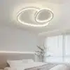 Kaasaegne LED laelamp, elegantsete ümarate joontega, paigaldatud helevalgesse magamistuppa, sobilik nii elutuppa kui söögituppa.