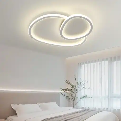 Kaasaegne LED laelamp, elegantsete ümarate joontega, paigaldatud helevalgesse magamistuppa, sobilik nii elutuppa kui söögituppa.