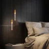 Elegantsed, energiasäästlikud ja moodsad rippvalgustid, millel on kuldsed toonid ja kristallilised detailid, ripuvad modernses magamistoas tumedal puidust seinal voodi kõrval.