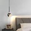 Energiatõhus LED ripplamp hõbedase viimistlusega magamistoa tumedal öökapil, pehme ja kaasaegne valgus ning halli nahast voodipeats aktsendina. Kujundus minimalistlikus interjööris naudinguks.