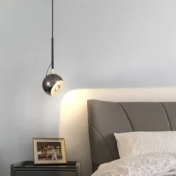 Energiatõhus LED ripplamp hõbedase viimistlusega magamistoa tumedal öökapil, pehme ja kaasaegne valgus ning halli nahast voodipeats aktsendina. Kujundus minimalistlikus interjööris naudinguks.